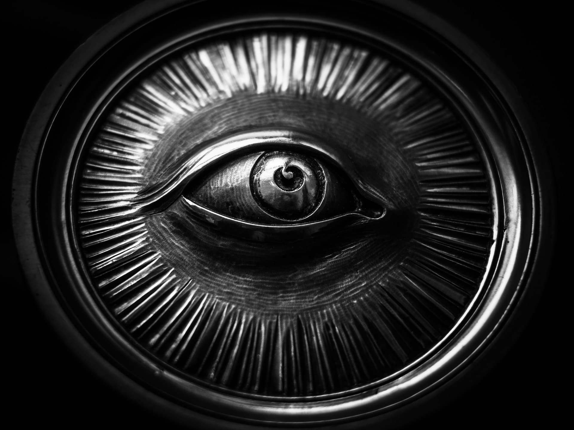 The underside of an aluminium can, its ring-pull opening shaped like a human eye, in black and white