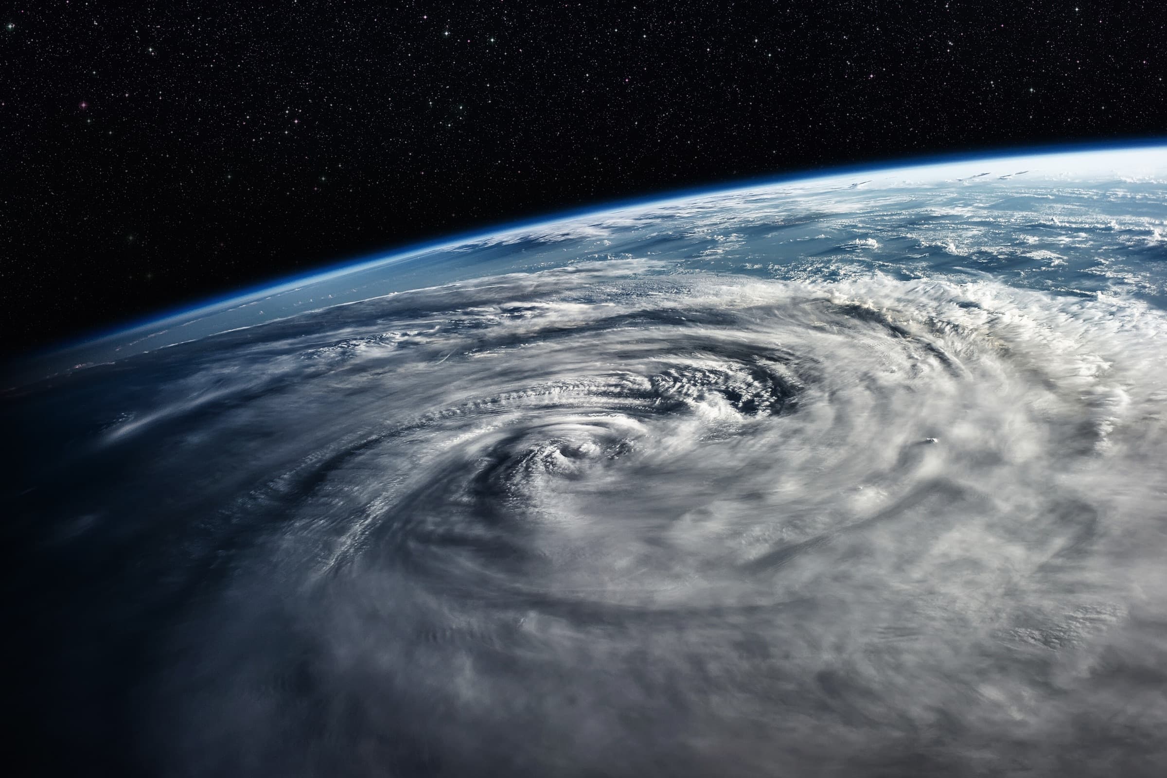 A cyclone seen from orbit, its eye at the centre of the spiral, the curve of the Earth behind