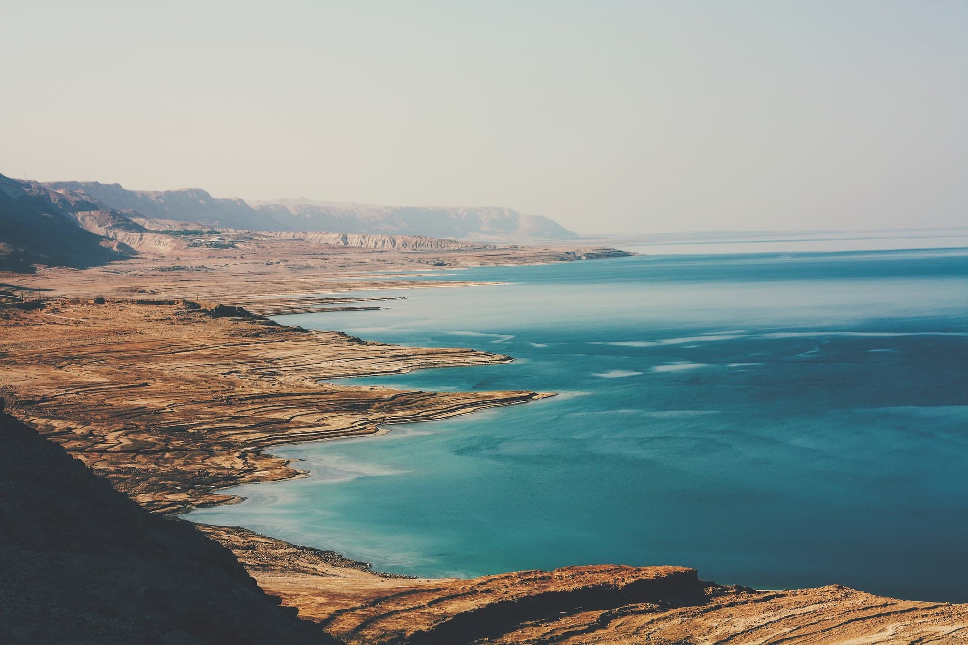 The Dead Sea shoreline, turquoise water against bare desert cliffs