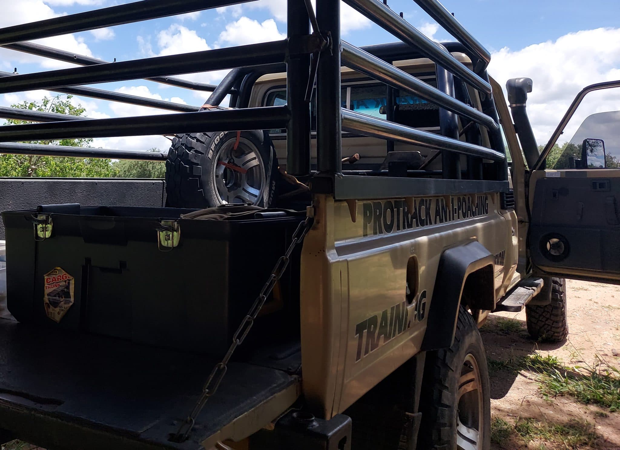 A pickup truck loaded with kit boxes and a spare wheel, “Protrack Anti-Poaching” and “Training” stencilled on the door